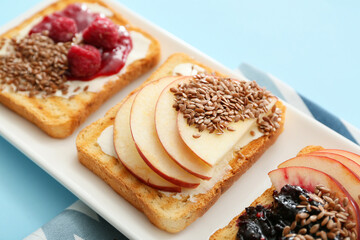 Tasty sandwiches with fruits and flax seeds on plate, closeup