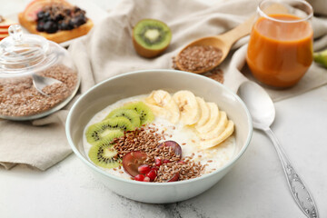 Tasty yoghurt with fruits and flax seeds in bowl on table