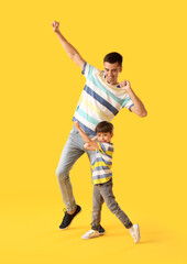 Fototapeta na wymiar Dancing man and his little son on color background