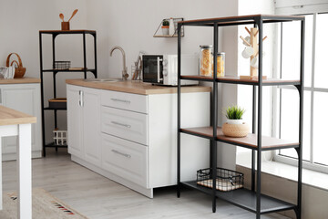 Interior of light kitchen with white counters, food and shelving units