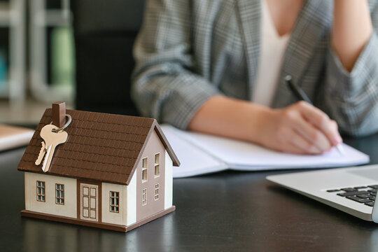 House model with keys on table of real estate agent, closeup