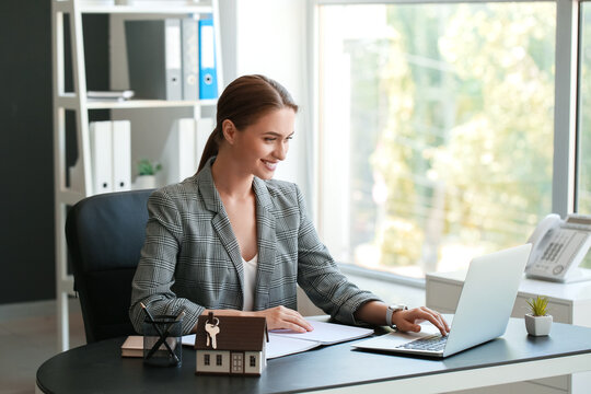 Real Estate Agent Working With Laptop At Table In Office