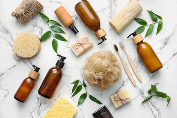 Set of bath supplies with loofah sponges and plant branches on light background