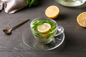 Cup of mint tea with lemon on dark wooden background