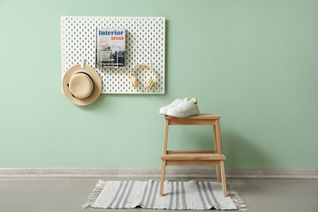 Wooden step stool with sneakers and peg board hanging on green wall