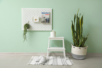 White step stool with tissue box and peg board hanging on green wall