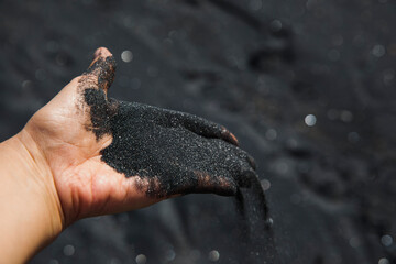 Volcanic sand falling from hand, close-up