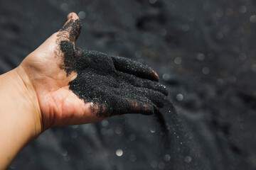 Volcanic sand falling from hand, close-up