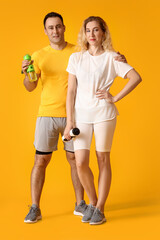 Sporty couple with bottles of water on color background