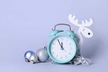 Christmas composition with alarm clock, balls and figure of deer on color background
