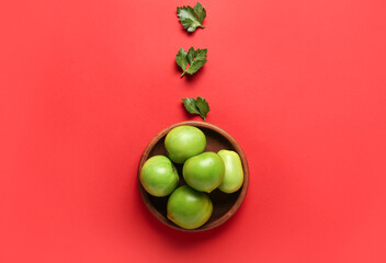 Composition with bowl of green tomatoes and parsley on color background