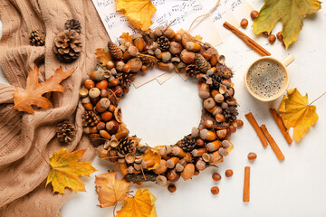 Beautiful acorn wreath with cup of coffee on light background