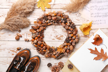 Beautiful acorn wreath and books on white wooden background