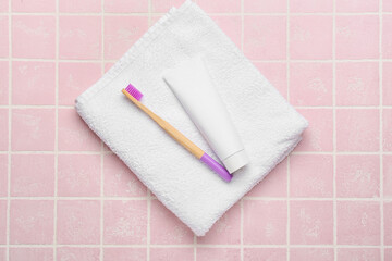 Obraz na płótnie Canvas Wooden toothbrush with paste and soft towel on color background