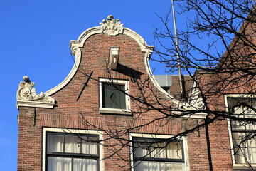 Historic House Facade with Bell Gable Close Up Against a Bright Blue Sky in Amsterdam, Holland