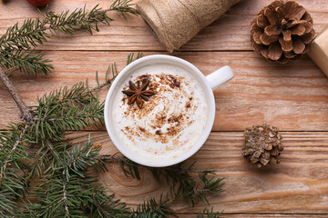 Cup of tasty coffee with cinnamon, pine cones and fir branch on wooden background