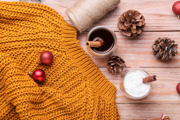 Glasses of tasty coffee with cinnamon, pine cones and Christmas balls on wooden background