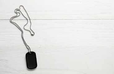 Military dog tag on white wooden background