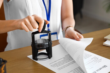 Female notary public attaching seal to document in office, closeup