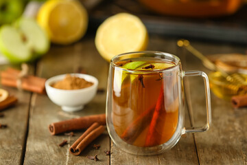 Glass cup of tasty fruit tea with cinnamon on table