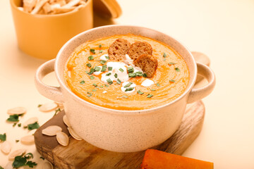 Pot with delicious pumpkin cream soup on color background, closeup