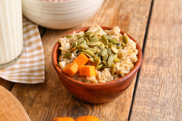 Bowl of tasty oatmeal with pumpkin on wooden background