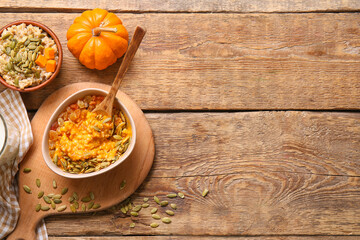 Bowls of tasty oatmeal with pumpkin on wooden background