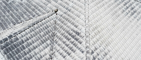 Obraz premium Close up top view of white gray roof tiles.Old dirty and clean roof. Modern roof tiles houseware. Construction equipment build a house.fix problem home,Rain damage to fix roof tiles.