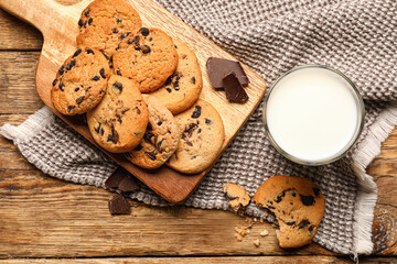 Board with tasty homemade cookies and glass of milk on wooden background