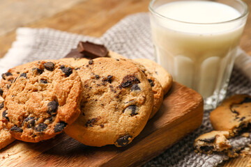 Board with tasty homemade cookies and glass of milk on table, closeup