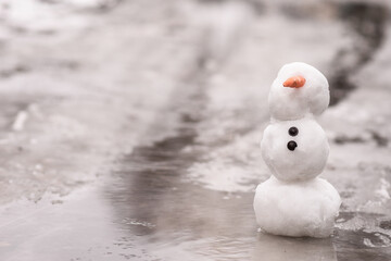 the concept of the arrival of spring. the snowman melt, stands in melted snow, ice and water. copy...