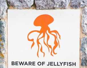 Orange warning sign for dangerous marine stingers or jellyfish in tropical Australia at the...