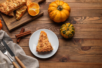 Plate and board with pieces of tasty pumpkin pie on wooden background