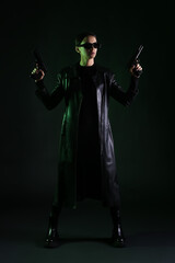 Woman with guns dressed in matrix style on dark background