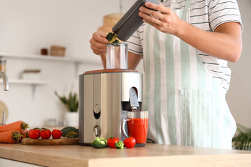 Young man preparing healthy vegetable juice in kitchen