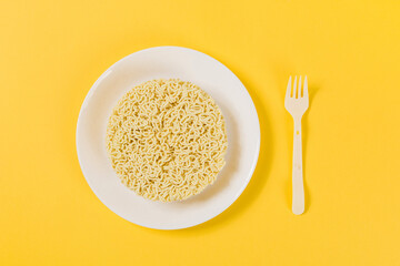 plate of  instant noodles with fork on yellow background