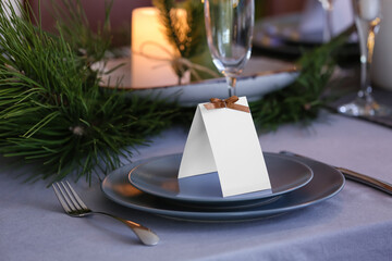 Dining table with setting for Christmas celebration and blank card indoors