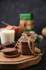 Wooden board with tasty chocolate cookies and on black background