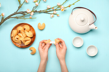 Female hands with Chinese fortune cookies and tea on color background