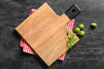 Wooden cutting board with micro green, Brussel sprouts and napkin on dark background