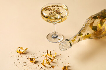 Glass of champagne, bottle and confetti on color background