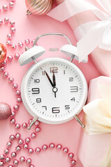 Stylish alarm clock, gift boxes and Christmas decor on pink background