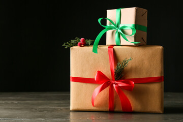 Stylish Christmas gift boxes on wooden table against dark background