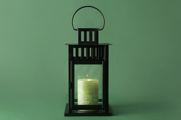 Beautiful Christmas lantern with burning candle on green background