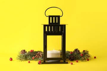 Beautiful Christmas lantern with candle and fir branches on yellow background