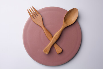 clock pink plate with wooden spoon and fork eating time meal concept
