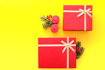 Composition with Christmas gift boxes, candles and fir branches on yellow background