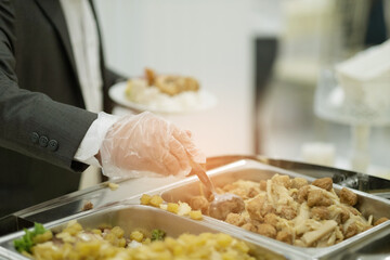a person wearing gloves scooping food, catering, dinner time, prevent Coronavirus disease (covid 19)