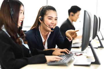 Group of happy asian smiling call center business operator customer help support team phone services agen working and talking with headset on desktop computer at call center office