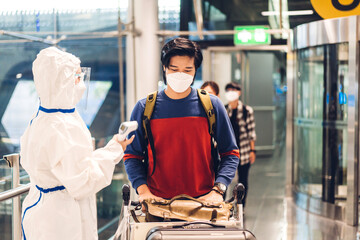 Doctor woman use infrared forehead thermometer for check body temperature scan travel passenger fever in quarantine for coronavirus omicron wearing safety mask at International terminal airport. - obrazy, fototapety, plakaty